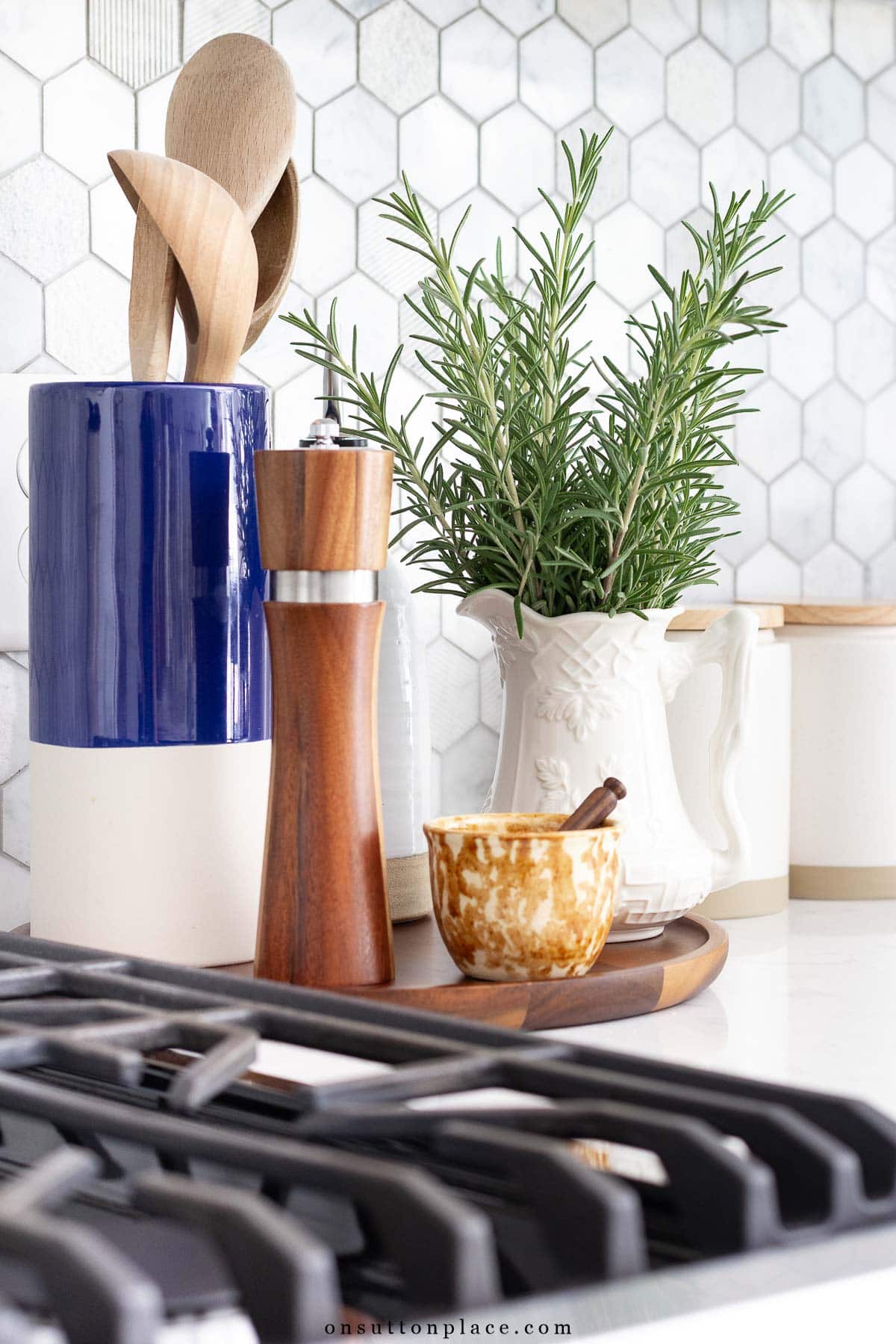 utensil crock and pitcher of rosemary beside stove on kitchen counter