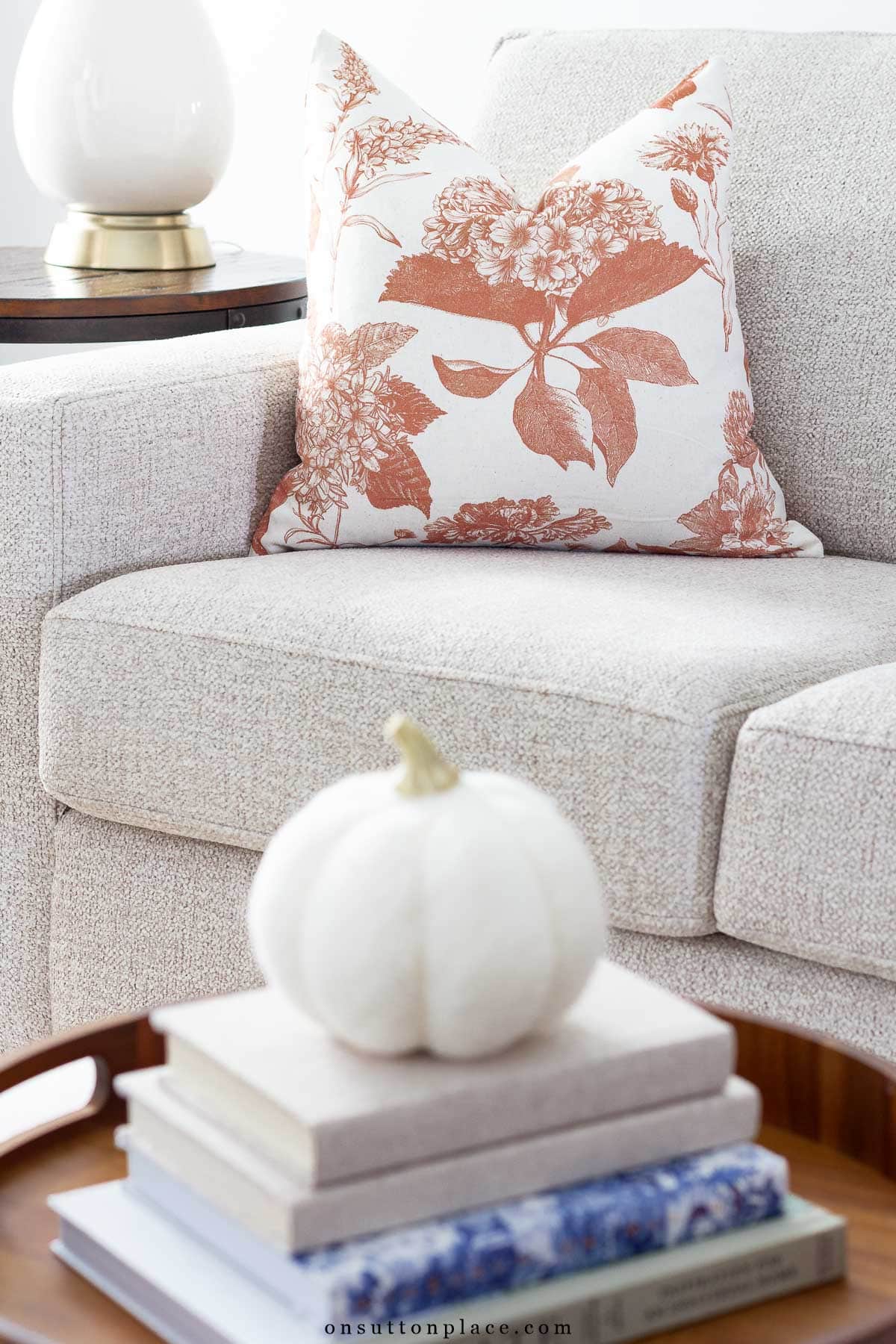 fall at home idea rust and ivory floral throw pillow on sofa books on coffee table